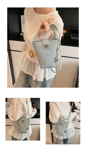 Détail du sac seau bleu clair avec texture cuir galet et fermoir rotatif argenté
