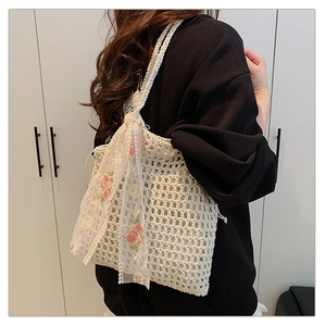 Detail of cream woven shoulder bag featuring floral lace ribbon on crochet mesh texture
