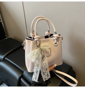 Détail du sac seau rose clair avec nœud en dentelle perlée et poignée nouée sur siège