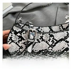 Close-up of adjustable silver-tone buckle and snakeskin texture on underarm bag