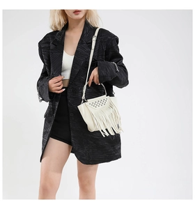 Dettaglio borsa bianca con frange borchie argento e manico in metallo su blazer