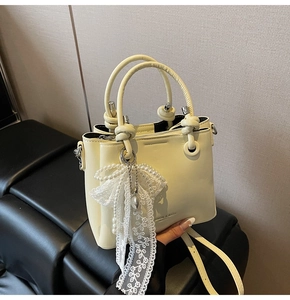 Détail du sac seau jaune clair avec lettrage mode et pendentif en dentelle de perles