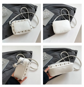 Detailweergave van witte PU-lederen crossbodytas met zilveren metalen studs en vierkante vorm