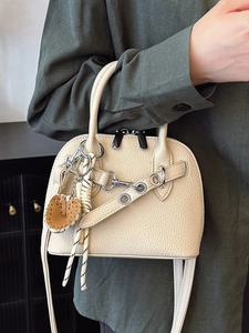 Elegant off-white lychee grain shell handbag with silver hardware and decorative charm