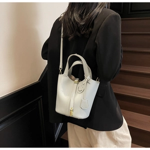 Detail of lychee pattern leather bucket bag with gold padlock on wooden stairs