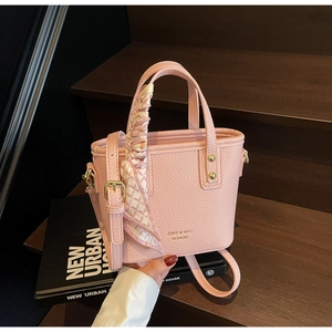 Close-up of pink litchi grain bucket bag with silk scarf handle and golden logo detail