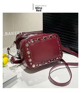 Detail van de wijnrode lederen crossbody tas met zilveren studs en ritssluiting boven