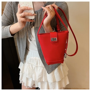 Détail du sac seau rouge montrant la texture cuir litchi et le fermoir pivotant argenté