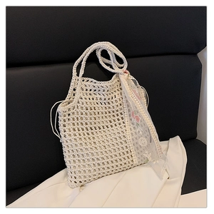 Detail of hollow woven beach bag featuring cream crochet texture and floral lace scarf