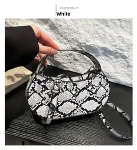 Detail of white snakeskin crescent bag with metal buckle and adjustable shoulder strap