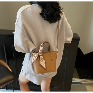 Close-up of brown lychee grain leather mini bucket bag with a checkered silk scarf