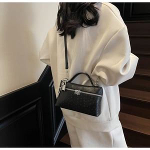 Detail of black ostrich embossed crossbody bag with silver lock and key ornament