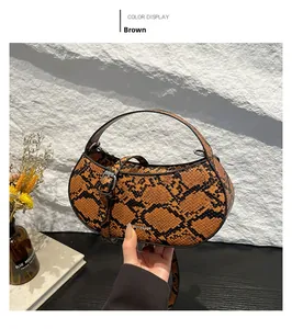 Detail of a brown python pattern crescent handbag with adjustable strap on stone background