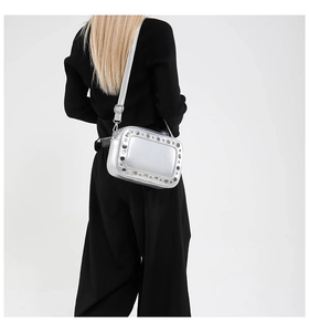 Detail van zilveren crossbodytas met studs gedragen op zwarte kledingstijl