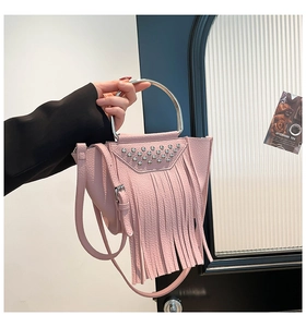 Dettaglio borsa rosa con nappe, borchie argentate e manico circolare in metallo stile street