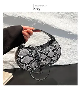 Close-up of a grey snakeskin crescent saddle bag with metallic buckle and handle