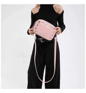 Detailweergave van een roze crossbodytas met metalen klinknagels en verstelbare schouderband