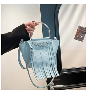 Dettaglio della borsa a tracolla azzurra con borchie argentate e lunghe nappe