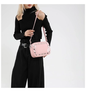 Borsa a tracolla alla moda in vernice rosa con dettagli di borchie argentate indossata da modella