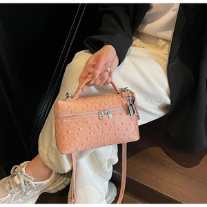 Detail of coral ostrich pattern handbag with silver hardware and padlock on the side