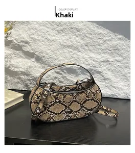 Detailed close-up of khaki snakeskin leather bag with silver hardware on black table