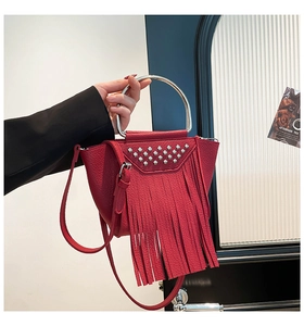 Dettagli della borsa in pelle rossa con borchie argentate, lunghe frange e manico in metallo