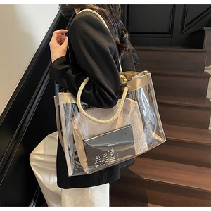 Detailed close-up of a clear PVC tote bag with gold trim and cream rope handles