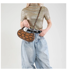 Detail shot of the snake pattern crescent bag texture with metal logo on a model