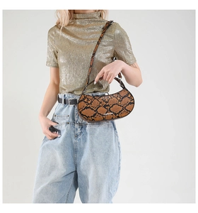 Chic brown snakeskin half-moon bag worn by model with adjustable shoulder strap