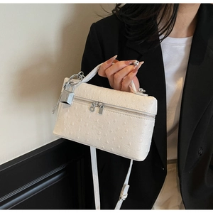 Detail of white ostrich embossed pattern leather handbag with silver metallic buckle accents