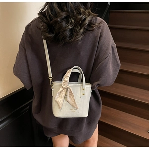 Detail of off-white lychee texture bucket bag with silk scarf handle on model