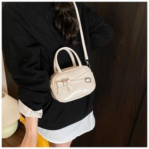 Detailed view of cream-white bowling handbag with ribbon bow and silver metal buckle