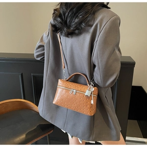 Detailed macro view of the brown ostrich pattern leather bag with metallic padlock detail