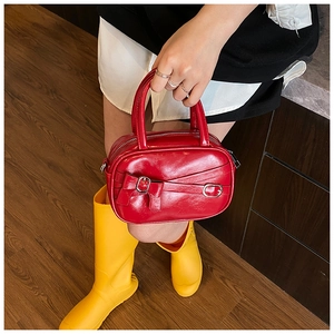 Detail of a shiny red bowling bag with bow decoration and silver buckles in street style