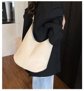 Detail of cream lychee texture leather tote bag worn by model in a casual business style