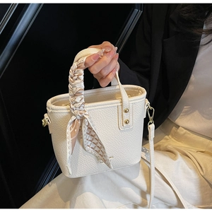 Close-up of white pebble grain leather bucket bag with elegant floral scarf on handle