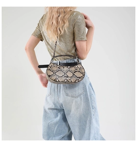 Chic oval handbag with snakeskin pattern, styled with blue jeans and golden top