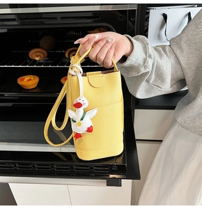 Détail du petit sac bandoulière jaune motif litchi avec un adorable canard suspendu