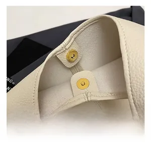 Close-up of golden magnetic buckle on cream lychee pattern leather tote bag
