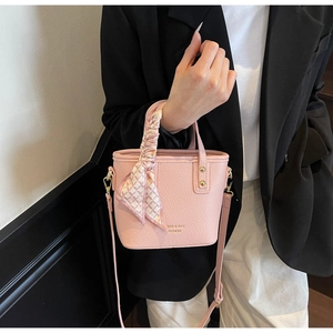 Close-up of pink lychee textured bucket bag with silk scarf handle and golden hardware