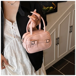 Detail of pink glossy leather handbag featuring a bow and silver-tone buckle decoration