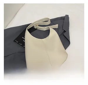 Close-up of minimalist cream hobo bag showing lychee grain leather and strap details