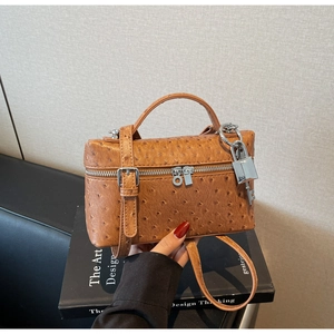 Detail of ostrich texture brown crossbody bag with silver padlock and key accessories