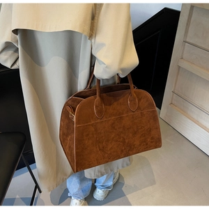Detalle del bolso tote grande de ante marrón con asas dobles y acabado texturizado