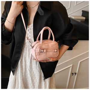 Pink bowling bag with bow detail and metal buckles shown on a model in a lifestyle setting