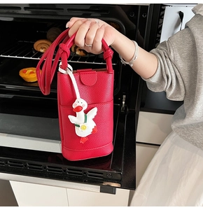 Détail du mini sac bandoulière rouge avec texture litchi et adorable breloque canard en 3D