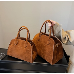 Detalle de bolsos de mano marrones de ante estilo británico en tamaños grande y pequeño