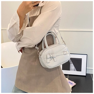 Close-up of minimalist handbag with bow detail and silver metal buckle on leather strap
