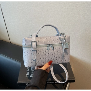 Detailed close-up of a light purple ostrich texture leather handbag with metal lock charm