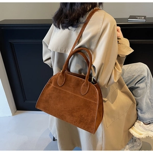 Detalle de un bolso de gamuza marrón de gran capacidad llevado por una modelo